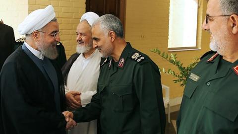 Iranian President Hassan Rouhani (L-2) shakes hands with Iranian Quds Force commander Qassem Soleimani (R-2) during the 21st Nationwide Assembly of the Islamic Revolution Guard. (Pool/Iranian Presidency Press Office/Anadolu Agency/Getty Images)