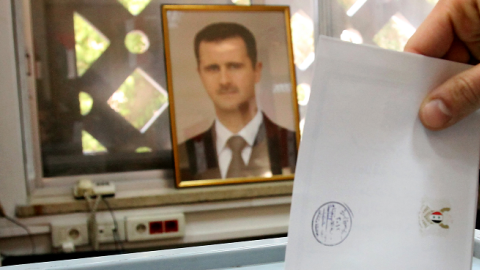 A Syrian man casts his ballot in front of a picture of Syrian President Bashar al-Assad at a polling station in Damascus on February 26, 2012 (ANWAR AMRO/AFP/Getty Images)