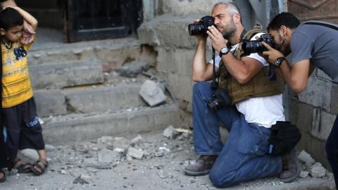New York Times Photographer Tyler Hicks (2ndR) takes pictures of Palestinians in Gaza City on July 16, 2014. (THOMAS COEX/AFP/Getty Images)