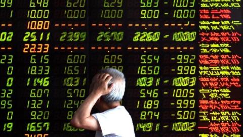 An investor looks through stock information at a trading hall in Shenyang, China, July 7, 2015. (Xinhua/Pan Yulong via Getty Images)