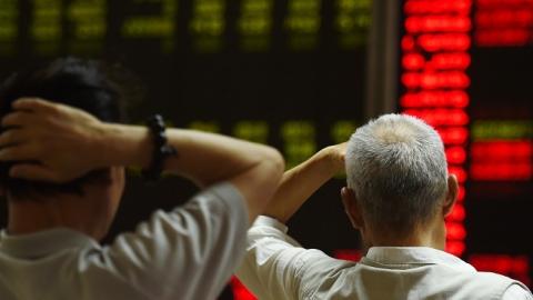 Investors look at screens showing stock market movements at a securities company in Beijing on July 14, 2015. (GREG BAKER/AFP/Getty Images)