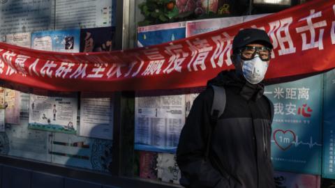 A Chinese man wears a protective mask as he walks by a health banner related to the coronavirus outbreak at a local market on March 4, 2020 in Beijing, China. (Kevin Frayer/Getty Images)