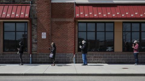 People line up exactly 6-feet-apart in front of a Westwood Wegmans store on Apr. 4, 2020 in Westwood, MA. With the coronavirus expected to peak in mid-April, grocery stores have cracked down on social distancing guidelines throughout the Boston area.