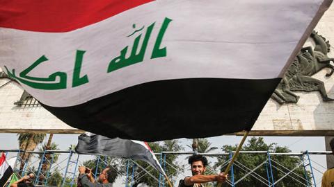 A demonstrator waves a large Iraqi national flag during an anti-government protest. (Photo by AHMAD AL-RUBAYE/AFP via Getty Images)