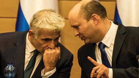 Naftali Bennett (R), leader of the Yamina right-wing alliance, speaks with Yair Lapid, leader of the Yesh Atid opposition centrist party attend first cabinet meeting at the Israeli Parliament (Photo by Ilia Yefimovich/picture alliance via Getty Images)