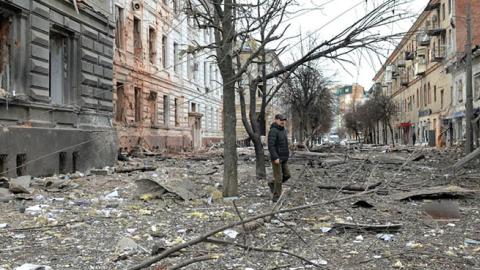 A pedestrian walks amid debris following a shelling in Ukraine's second-biggest city of Kharkiv on March 7, 2022. (Photo by Sergey Bobok/AFP via Getty Images)