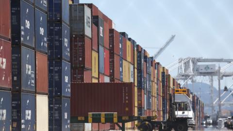 A truck drives by stacks of shipping containers at the Port of Oakland on May 20, 2022 in Oakland, California.