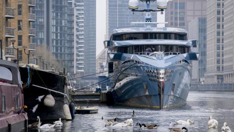 A local boat resident feeds local birdlife alongside the 58m (192ft) £38m super-yacht 'Phi' which remains seized at 'Dollar Bay' in London Docklands, impounded by the UK's National Crime Agency (NCA) because of sanctions against Putin associates during the Russian invasion of Ukraine, on 30th March 2022, in London, England. The Phi has its own swimming pool and infinite wine cellar, according to its Dutch builders. Its ownership is uncertain but it is believed to be owned by a Russian businessman with links