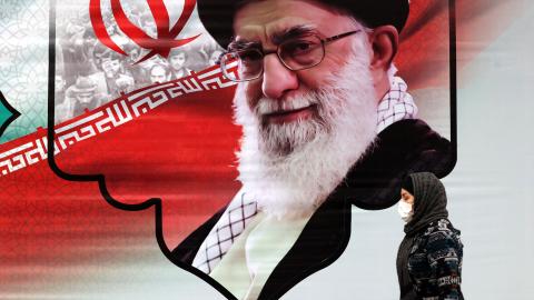 An Iranian woman walks past a mural showing Iran's Supreme Leader Ayatollah Ali Khamenei in the capital Tehran on March 9, 2022. (Photo by ATTA KENARE / AFP) (Photo by ATTA KENARE/AFP via Getty Images)