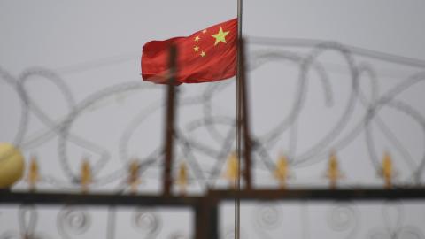 The Chinese flag behind razor wire at a housing compound in Yangisar in China's western Xinjiang region. (Greg Baker/AFP via Getty Images)