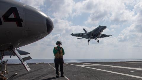 Aviation Boatswain's Mate observes an F/A-18E Super Hornet attached to the "Tomcatters" of Strike Fighter Squadron landing on the flight deck of the world’s largest aircraft carrier USS Gerald R. Ford in the Eastern Mediterranean Sea on October 13, 2023. (Jacob Mattingly via DVIDS)