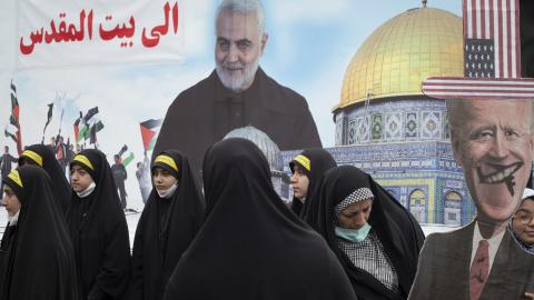 A veiled Iranian woman holds an effigy of US President Joe Biden while standing in front of a portrait of the former commander of Iran’s Islamic Revolutionary Guard Corps (IRGC) Quds Force, General Qasem Soleimani, and an image of al-Aqsa mosque during a rally commemorating the International Quds Day in downtown Tehran on April 29, 2022. (Photo by Morteza Nikoubazl/NurPhoto via Getty Images)