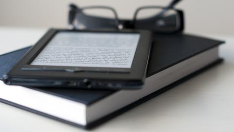 E-Reader and book with reading glasses.