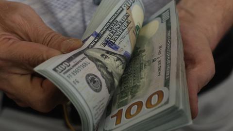 A teller flicks through a bundle of US dollar bills at an exchange office in Ankara on July 20, 2023. (Adem Altan/AFP via Getty Images)