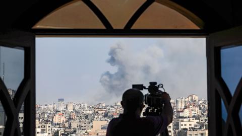 An AFPTV cameraman films while smoke plumes billow during Israeli air strikes in Gaza City on October 12, 2023. (Photo by MOHAMMED ABED / AFP) (Photo by Mohammed Abed/AFP via Getty Images)