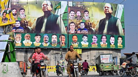 People ride past large banners of Pakistan's former Prime Minister Nawaz Sharif displayed along a street ahead of his arrival in Lahore on October 19, 2023. (Arif Ali/AFP via Getty Images)