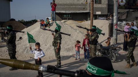 A young boy holds up a Hamas flag in between Palestinian Hamas militant during a military show in the Bani Suheila district of Gaza on July 20, 2017. (Chris McGrath via Getty Images)