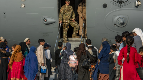 Service members prepare to board evacuees onto a C-17 Globemaster lll on Aug. 22, 2021, at Al Udeid Air Base, Qatar. ( Kylie Barrow via DVIDs) 