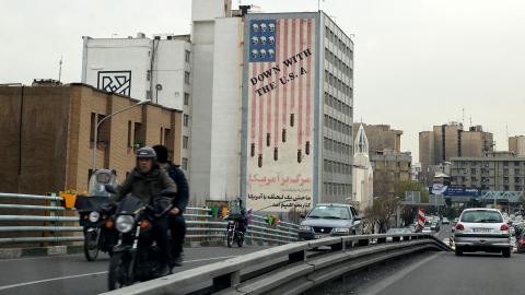 Vehicles drive on a street across from an anti-US mural in Tehran on March 12, 2022. (Photo by ATTA KENARE/AFP via Getty Images)