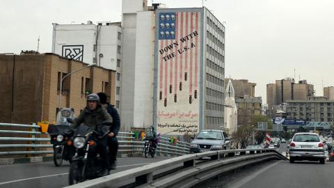 Vehicles drive on a street across from an anti-US mural in Tehran on March 12, 2022. (Photo by ATTA KENARE/AFP via Getty Images)