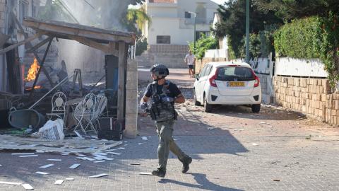 A member of the Israeli forces runs past a fire raging in a house in Ashkelon following a rocket attack from the Gaza Strip on southern Israel on October 7, 2023. Palestinian militant group Hamas has launched a "war" against Israel, Defence Minister Yoav Gallant said, after barrages of rockets were fired from the Gaza Strip into Israeli territory on October 7. (Photo by AHMAD GHARABLI / AFP) (Photo by AHMAD GHARABLI/AFP via Getty Images)