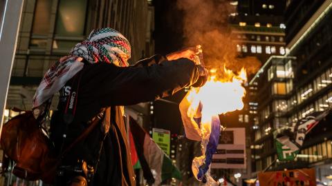 A pro-Palestine supporter burns an Israeli flag during a rally near the Rockefeller Center Christmas Tree Lighting on November 29, 2023, in New York City. (David Dee Delgado via Getty Images)