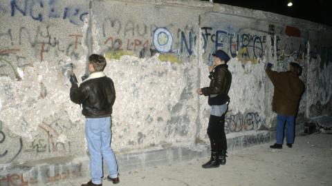 People with a chisel and sledgehammer participate in the destruction of the Berlin Wall near by the Brandenburg Gate as they celebrate the first New Year in a unified Berlin since World War II on December 31, 1989, in Berlin, Germany. (Thierry Monasse via Getty Images)