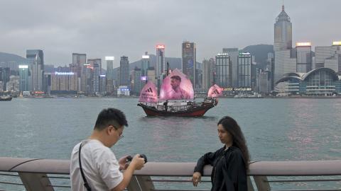 A fan poses for a photo as a sailing ship bearing a portrait of Inter Miami CF's Argentine forward Lionel Messi sails across the Victoria Harbor on February 3, 2024, in Hong Kong, China. (VCG/VCG via Getty Images)