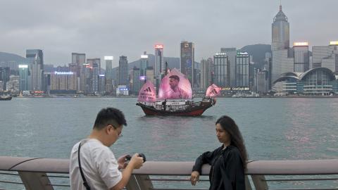  A fan poses for a photo as a sailing ship bearing a portrait of Inter Miami CF's Argentine forward Lionel Messi sails across the Victoria Harbor on February 3, 2024, in Hong Kong, China. (VCG/VCG via Getty Images)