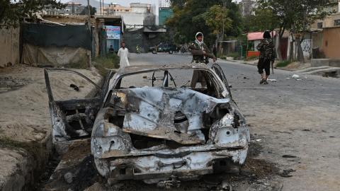 Taliban fighters stand guard near a damaged car after multiple rockets were fired in Kabul on August 30, 2021. (Photo by Wakil Kohsar/AFP via Getty Images)