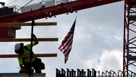 An American flag flies from a crane as a construction worker helps build a mixed-use apartment complex on January 25, 2024, in Los Angeles, California. (Photo by Mario Tama/Getty Images)
