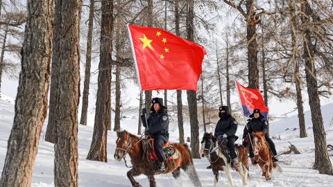 Police officers on horseback with national flags patrol the border in Xinjiang province, China, on December 29, 2023. (Costfoto/NurPhoto via Getty Images)