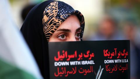 An Iranian citizen holds a placard in Tehran during a demonstration to support Iran's drone and missile attacks on Israel on April 15, 2024. (Photo by Fatemeh Bahrami/Anadolu via Getty Images)