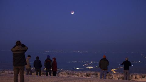 Israelis looks at a full lunar eclipse from Jerusalem’s Mount Scopus on December 10, 2011. (Menahem Kahana/AFP via Getty Images.)