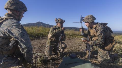 U.S. Marine Corps Sgt. Hunter Heinsohn, left, a signals intelligence operator and analyst, Cpl. Adam Domagalaski, right, an intelligence, surveillance and reconnaissance systems engineer, both with 3rd Radio Battalion, III Marine Expeditionary Force Information Group, coordinate an electronic attack 6-line with Lance Cpl. Jackie Wu, center, a rifleman with 2nd Battalion, 2nd Marine Regiment, 3d Marine Division, during the field training exercise portion of Resolute Dragon 23 at Japan Ground Self-Defense For