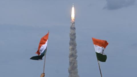 People wave Indian flags as an Indian Space Research Organisation (ISRO) rocket carrying the  Chandrayaan-3 spacecraft lifts off from the Satish Dhawan Space Centre in Sriharikota, an island off the  coast of southern Andhra Pradesh state, on July 14, 2023. (Photo by R.Satish Babu/AFP via Getty Images)