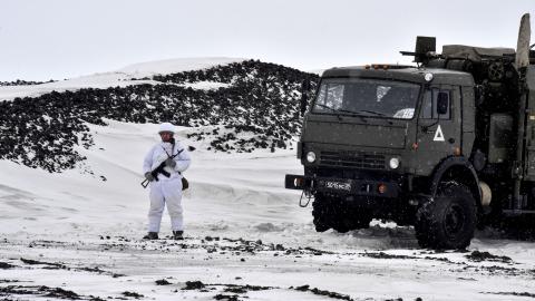 A Russian serviceman stands guard by a military truck on the island of Alexandra Land on May 17, 2021. (Maxime Popov/AFP via Getty Images)