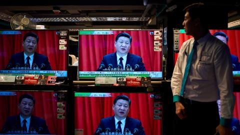 An electronics shop employee in Hong Kong on October 18, 2017, looks at television sets showing a news report on China's President Xi Jinping's speech at the opening session of the Chinese Communist Party's five-yearly Congress. (Anthony Wallace/AFP via Getty Images)