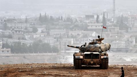 Turkish soldiers on a tank sit opposite the town of Ain al-Arab, Syria, on October 11, 2014. (Aris Messinis via Getty Images)