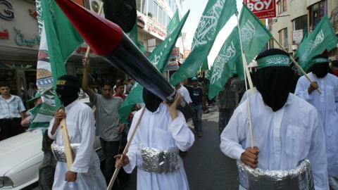 Masked Palestinian youths dressed as suicide bombers carry Hamas flags and a makeshift Qassam rocket during a rally organized by Hamas, in the West Bank City of Ramallah, on September 22, 2005 (Jamal Aruri/AFP via Getty Images)