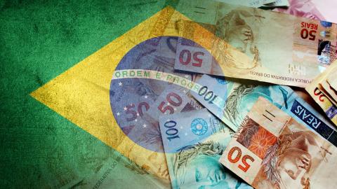 Brazilian reais cash bills and the flag of Brazil. (Getty Images)