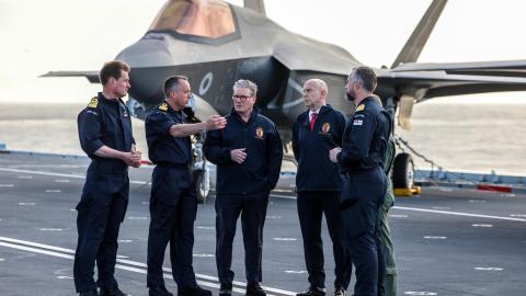 Britain's Prime Minister Keir Starmer and Britain's Defence Secretary John Healey stand in front of a Royal Navy F-35B Lightning fighter jet on the flight deck of the British aircraft carrier HMS Prince Of Wales on April 24, 2025. (Richard Pohle via Getty Images)