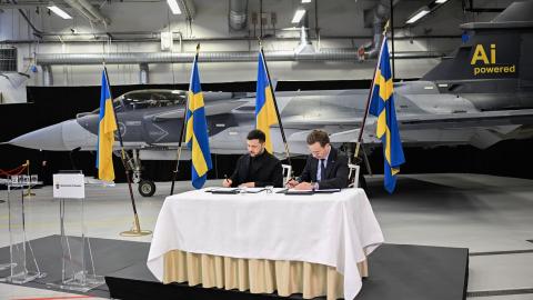 Swedish Prime Minister Ulf Kristersson (R) and Ukrainian President Volodymyr Zelensky sign documents during a joint press conference in front of a Gripen fighter jet in Linkoping, Sweden, on October 22, 2025, after talks on Russia's ongoing of aggression against Ukraine and the countries' deepening defense cooperation. Swedish Prime Minister Ulf Kristersson said on October 22 that Sweden and Ukraine had signed a letter of intent to develop air capabilities, which could see Ukraine buy up to 150 Gripen fight