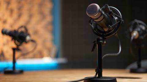 A microphone on a wooden table in a recording studio during a podcast. (Getty Stock Photo)