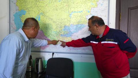 Caption Two men point at a map in an office on the grounds of the Saritag antimony mine in western Tajikistan on August 26, 2025. (Getty Images)