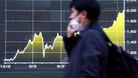 A man walks past an electronic board displaying the movement of 10-year government bonds in Tokyo on December 22, 2025. (Getty Images)