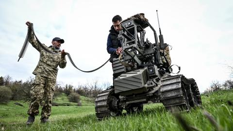 A soldier and a design engineer load a machine gun mounted on a ground robotic complex during trials at a training ground on April 10, 2026. (Getty Images) 