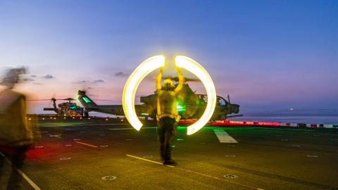 A US sailor assigned to Wasp-class amphibious assault ship USS Boxer signals an AH-1Z Viper to take off during flight operations in the South China Sea on June 13, 2026. (US Marine Corps)