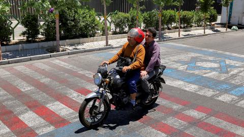 Caption A man rides a scooter along a road painted in the colours of the US and Israeli flags, in Tehran on May 26, 2026. (Getty Images) Share to Twitter