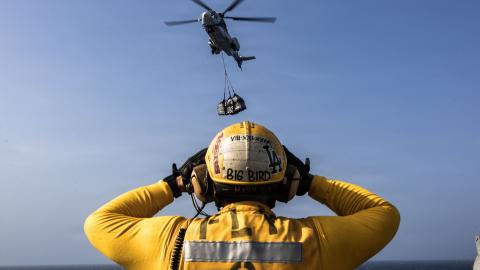 A U.S. Sailor directs a Eurocopter AS-332 Super Puma on the flight deck of Nimitz-class aircraft carrier USS Abraham Lincoln (CVN 72) during a replenishment-at-sea with fleet replenishment oiler USNS Henry J. Kaiser (T-AO-187), Aug. 16, 2026. Abraham Lincoln is deployed to the U.S. 5th Fleet area of operations to support maritime security and stability in the Middle East. (U.S. Navy photo)